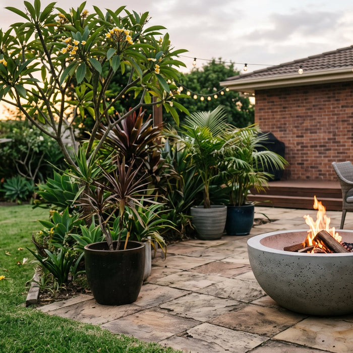 Round concrete fire bowl burning on a paved courtyard at dusk
