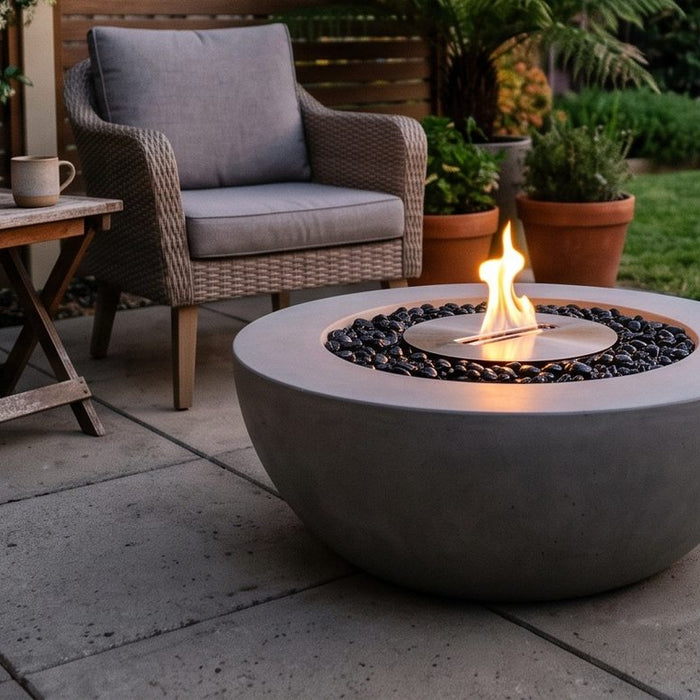 Round concrete bioethanol fire bowl with a clean flame on a suburban patio at dusk