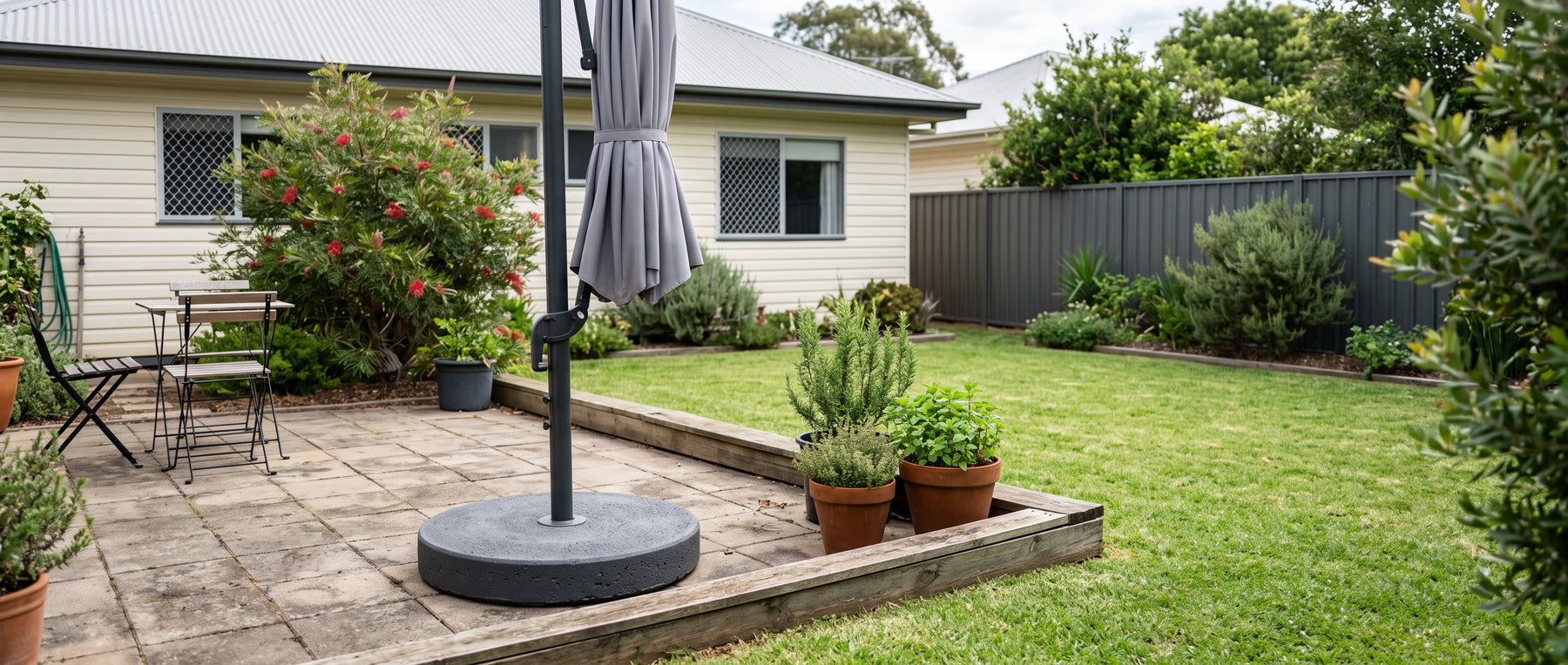 Heavy round concrete umbrella base at the foot of a cantilever umbrella stand