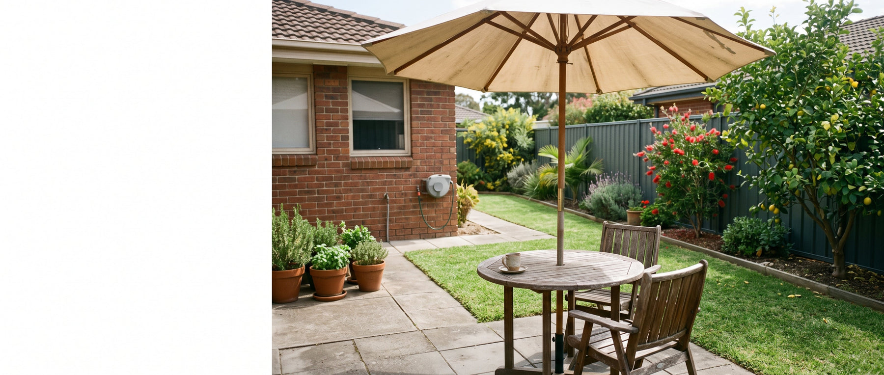 Round market-style patio umbrella over a small cafe table in a tidy Australian suburban courtyard