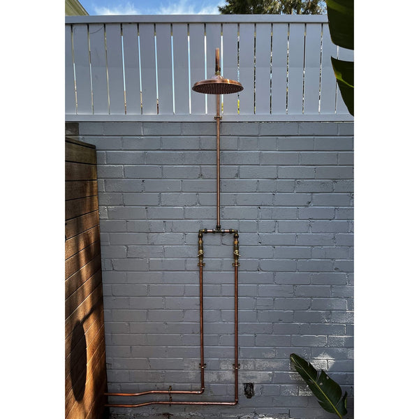 Handmade Banksia copper and brass hot and cold outdoor shower mounted against a wall.