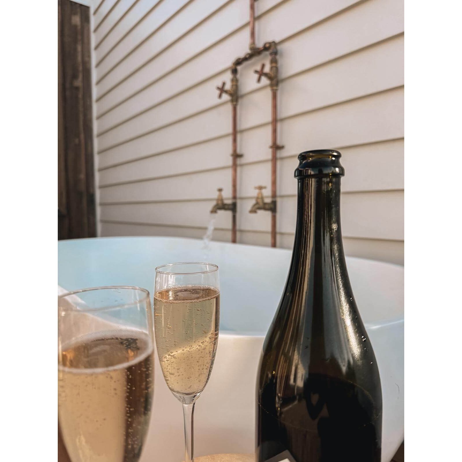 Handmade Banksia copper and brass hot and cold outdoor shower mounted against a wall.