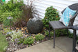 Small Stacked Slate Sphere fountain bubbling over river stones in a garden