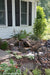 A small pondless waterfall built with the Aquascape DIY Backyard Waterfall Kit, cascading over rock into gravel beside a house