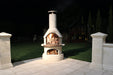 Buschbeck Rondo Outdoor Fireplace lit at night in a family backyard