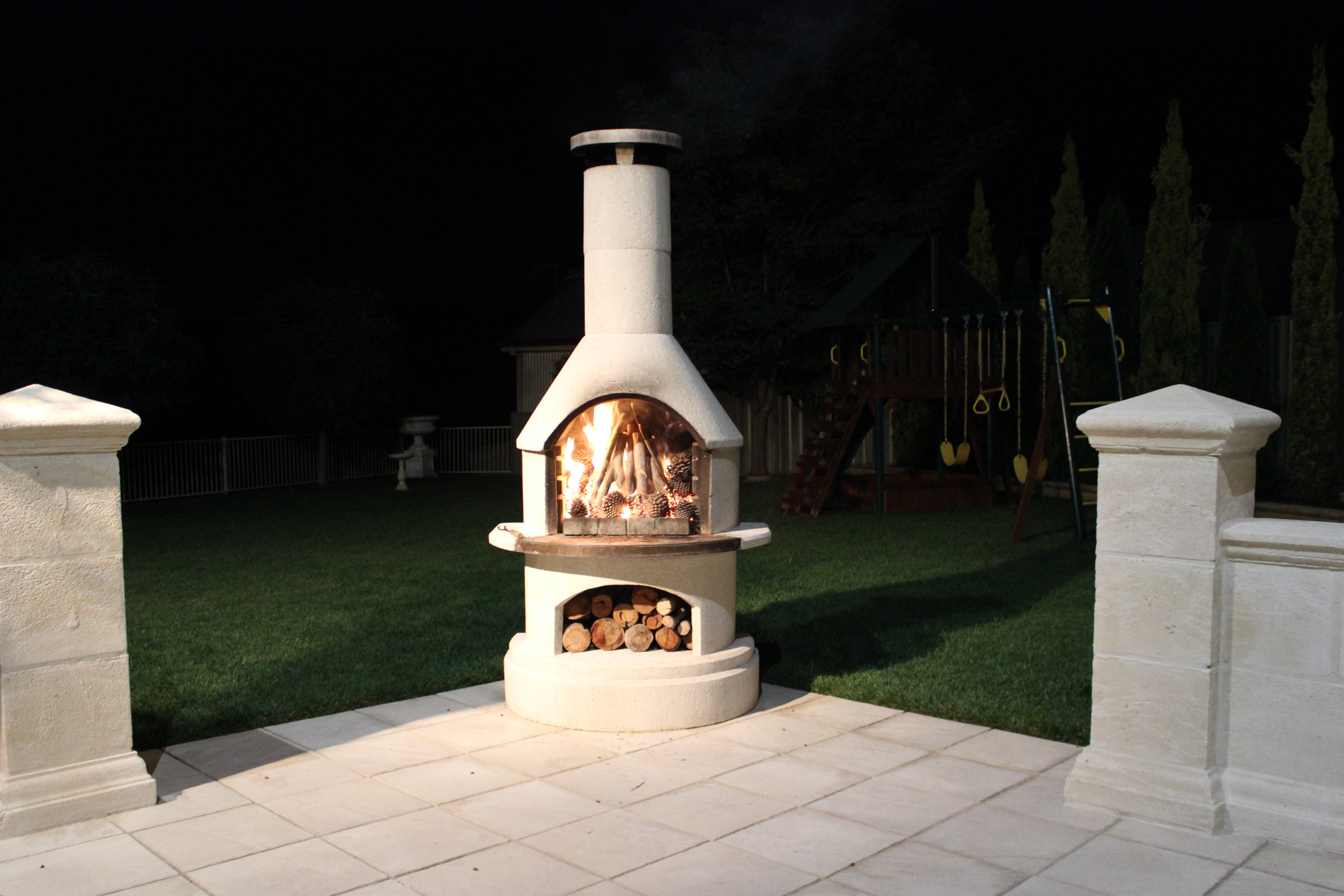 Buschbeck Rondo Outdoor Fireplace lit at night in a family backyard