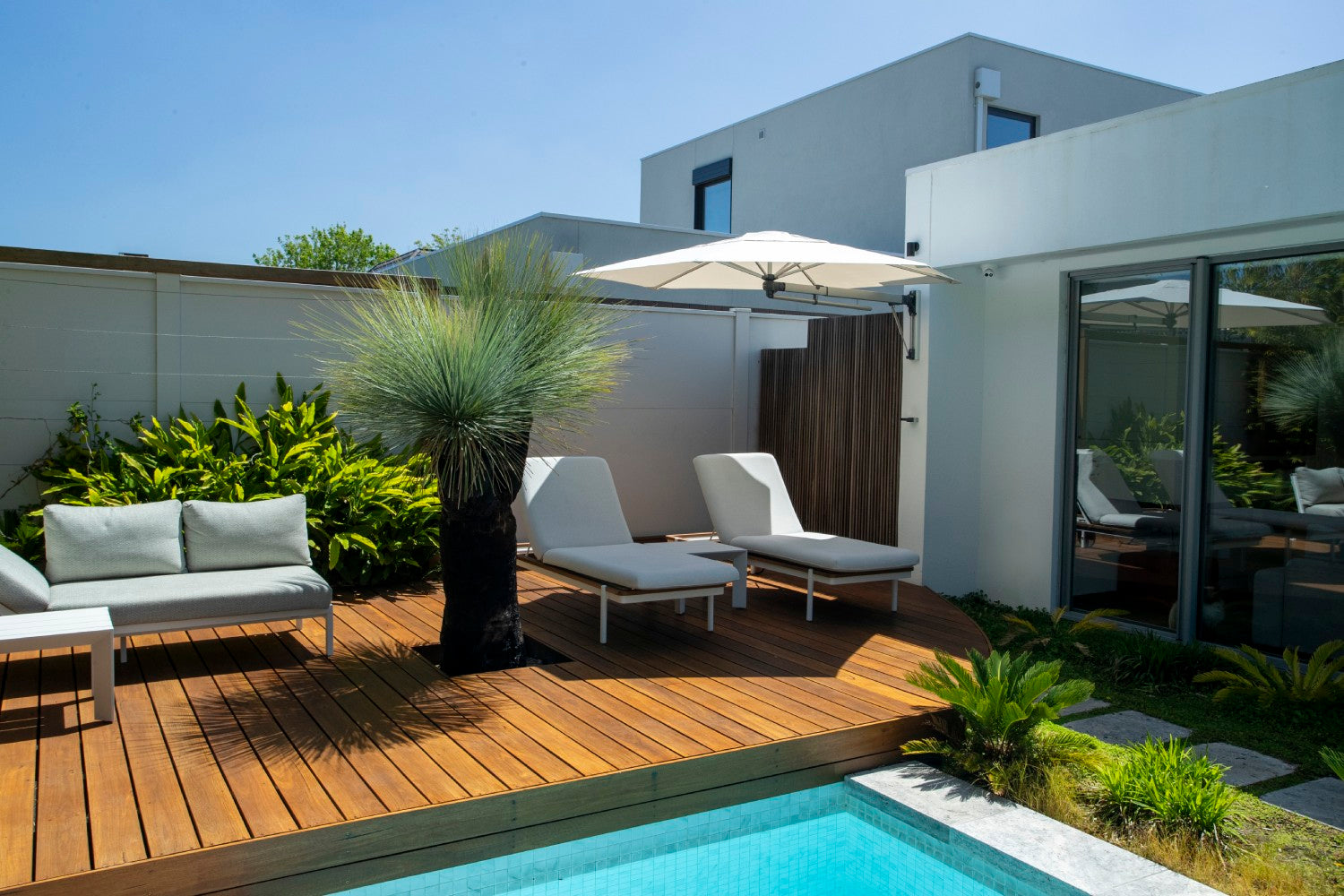 Shadowspec Retreat hexagon wall-mounted umbrella over a pool deck lounge setting
