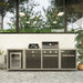 Coleman Revolution Dual Fuel outdoor kitchen in Black Gloss with a charcoal kettle, three burner gas grill, fridge and storage modules on a paved courtyard