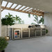 Angled view of the full Coleman Revolution Dual Fuel outdoor kitchen run under a pergola beside palms