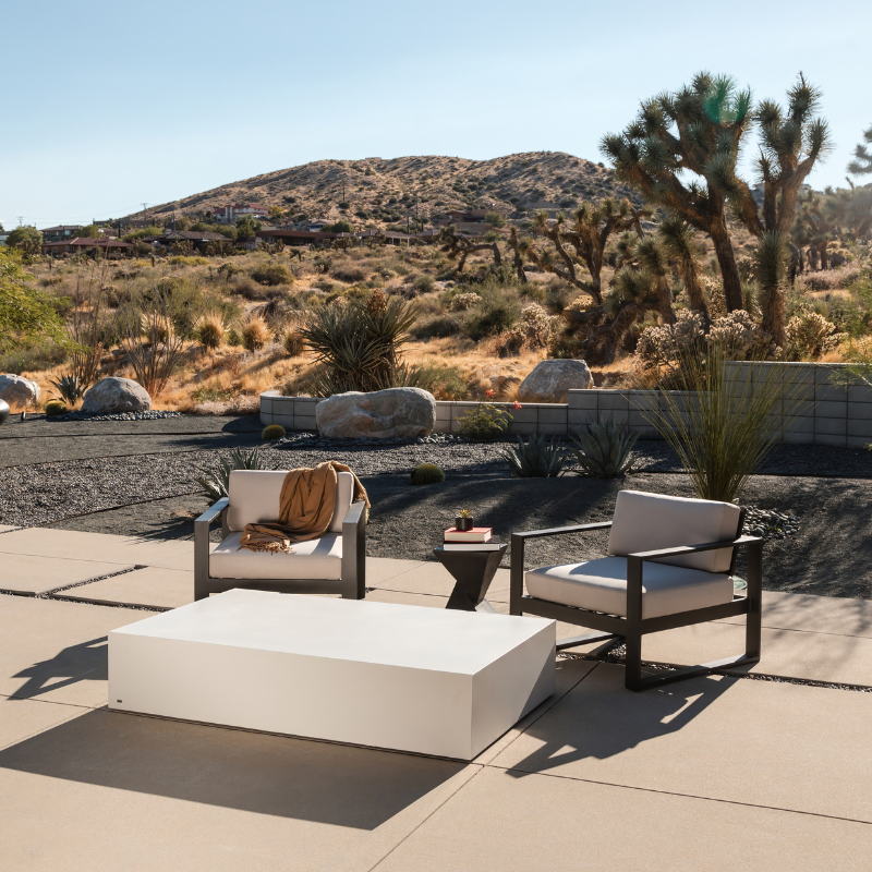 Move 65 rectangular concrete coffee table in outdoor desert landscape patio setting with modern seating