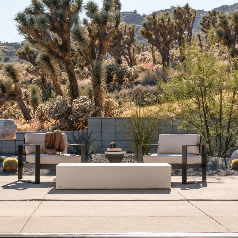 Move 65 rectangular concrete coffee table in bone white finish styled on an outdoor patio with lounge chairs.