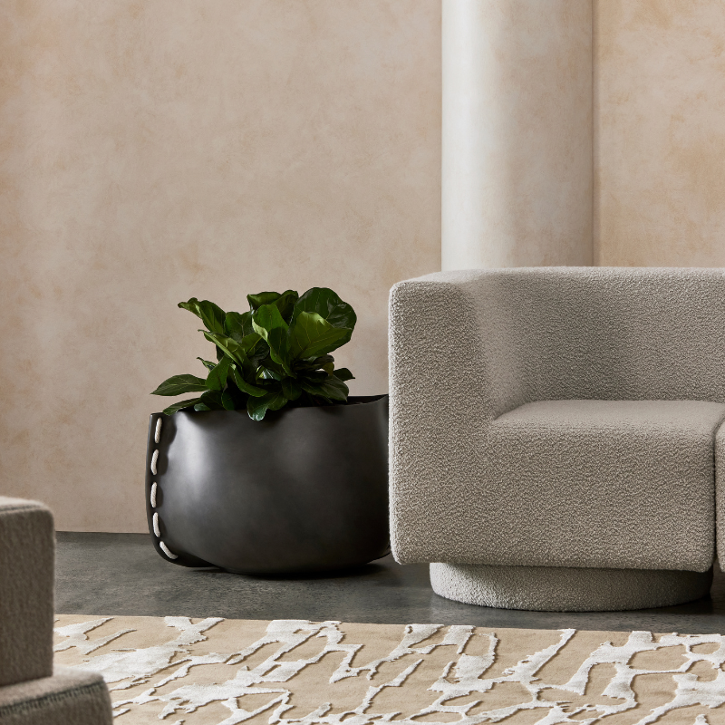 Stitch 25 concrete planter styled indoors beside a modern lounge chair with leafy plant
