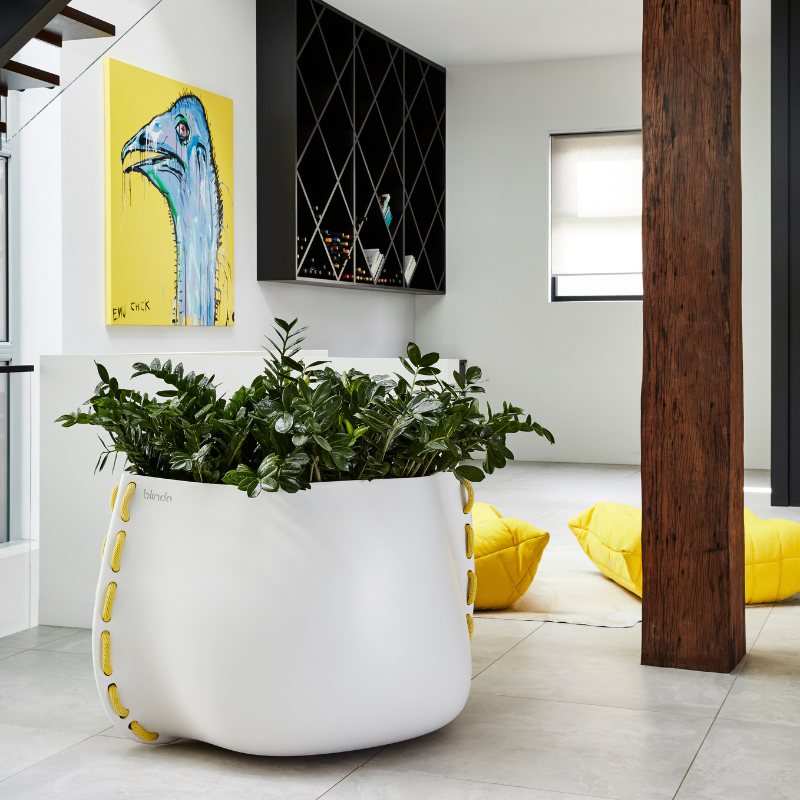 Blinde Stitch 125 white concrete planter with yellow stitched accents in a contemporary interior with artwork and modern furniture