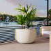 Blinde Stitch 125 white concrete planter with yellow stitched accents placed on a balcony overlooking a waterfront.
