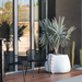 Blinde Stitch 50 white concrete planter with orange stitched rope detailing on a modern patio beside black outdoor chairs