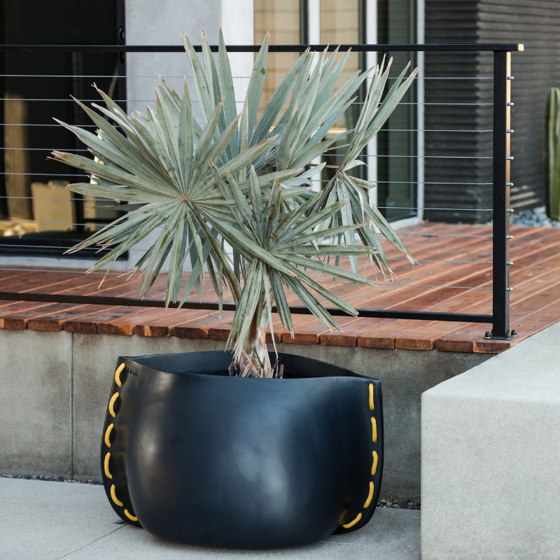 Blinde Stitch 75 concrete planter with yellow stitch detail displayed on an outdoor patio with a palm plant.