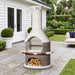 Buschbeck Rondo 3-in-1 outdoor fireplace, BBQ and pizza oven in Mocha with copper shelf insert, on a bluestone terrace beside a white weatherboard home