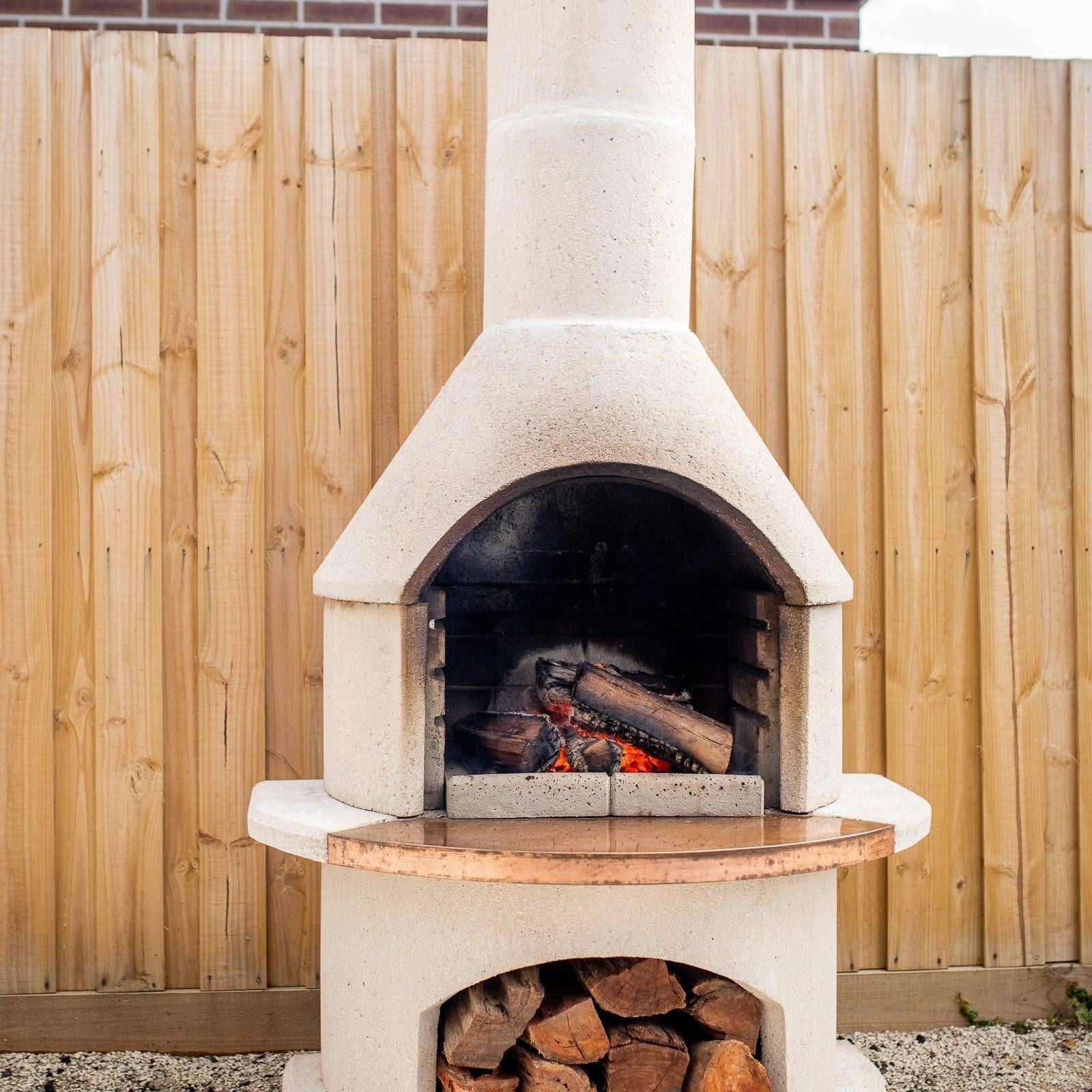 Buschbeck Rondo Outdoor Fireplace and Pizza Oven Kit with the fire lit in a backyard setting
