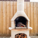 Buschbeck Rondo Outdoor Fireplace and Pizza Oven Kit with the fire lit in a backyard setting