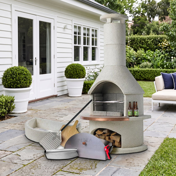 Buschbeck Rondo 3-in-1 outdoor fireplace, BBQ and pizza oven kit in White with pizza oven door, base extension, peels and cutter, on a bluestone terrace beside a white weatherboard home