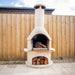 Buschbeck Rondo 3-in-1 outdoor fireplace in White, lit in an Australian backyard against a timber paling fence