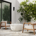 White Circ 40 round coffee table on a modern patio with wooden lounge chairs and greenery