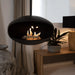 Cocoon Aeris Hanging Bioethanol Fireplace in matt black hanging in a living room beside a timber console