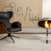 Cocoon Pedestal Bioethanol Fireplace in stainless steel beside a leather lounge chair