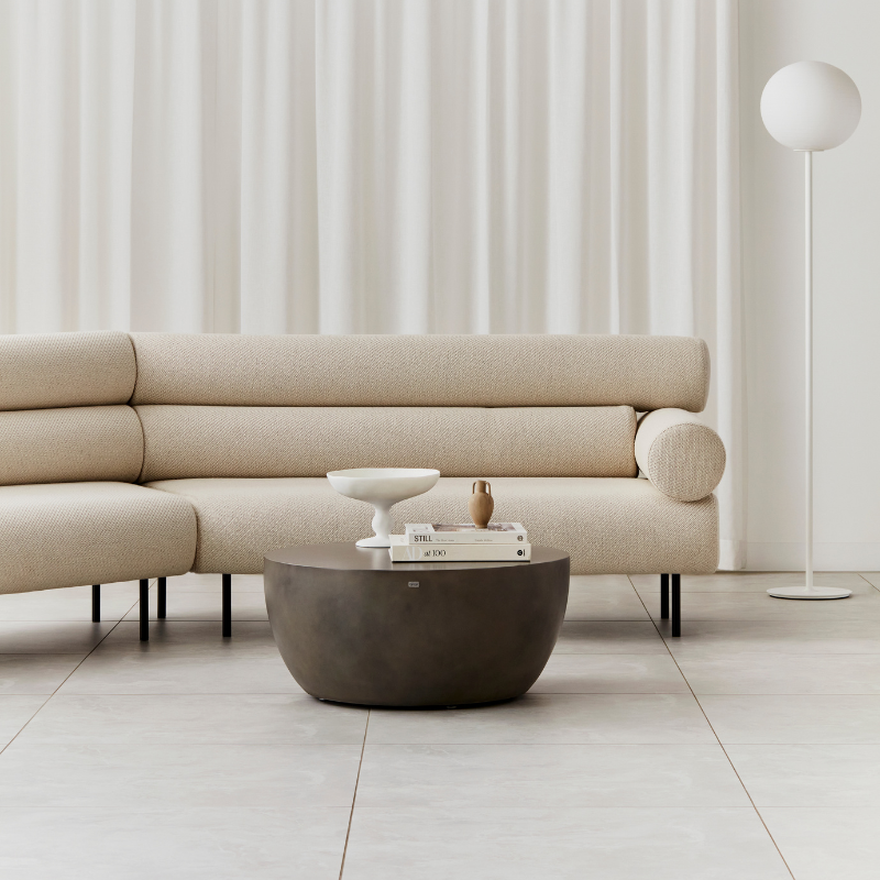 Curv 30 round coffee table in bronze finish styled in a modern living room with sofa and decor