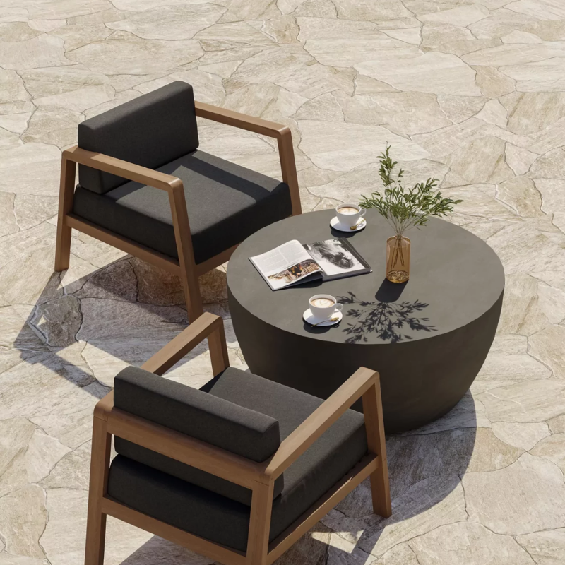 Curv 30 round outdoor coffee table in dark finish between two lounge chairs with coffee cups and decor