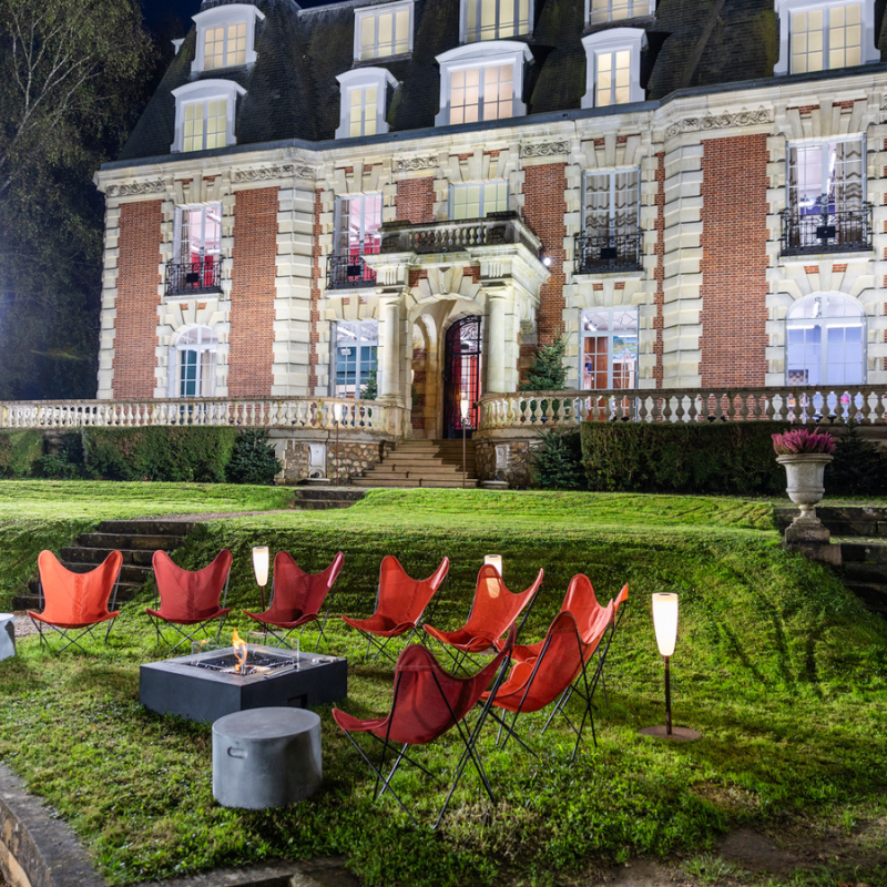EcoSmart Base 40 fire table in garden seating area with red chairs in front of large house
