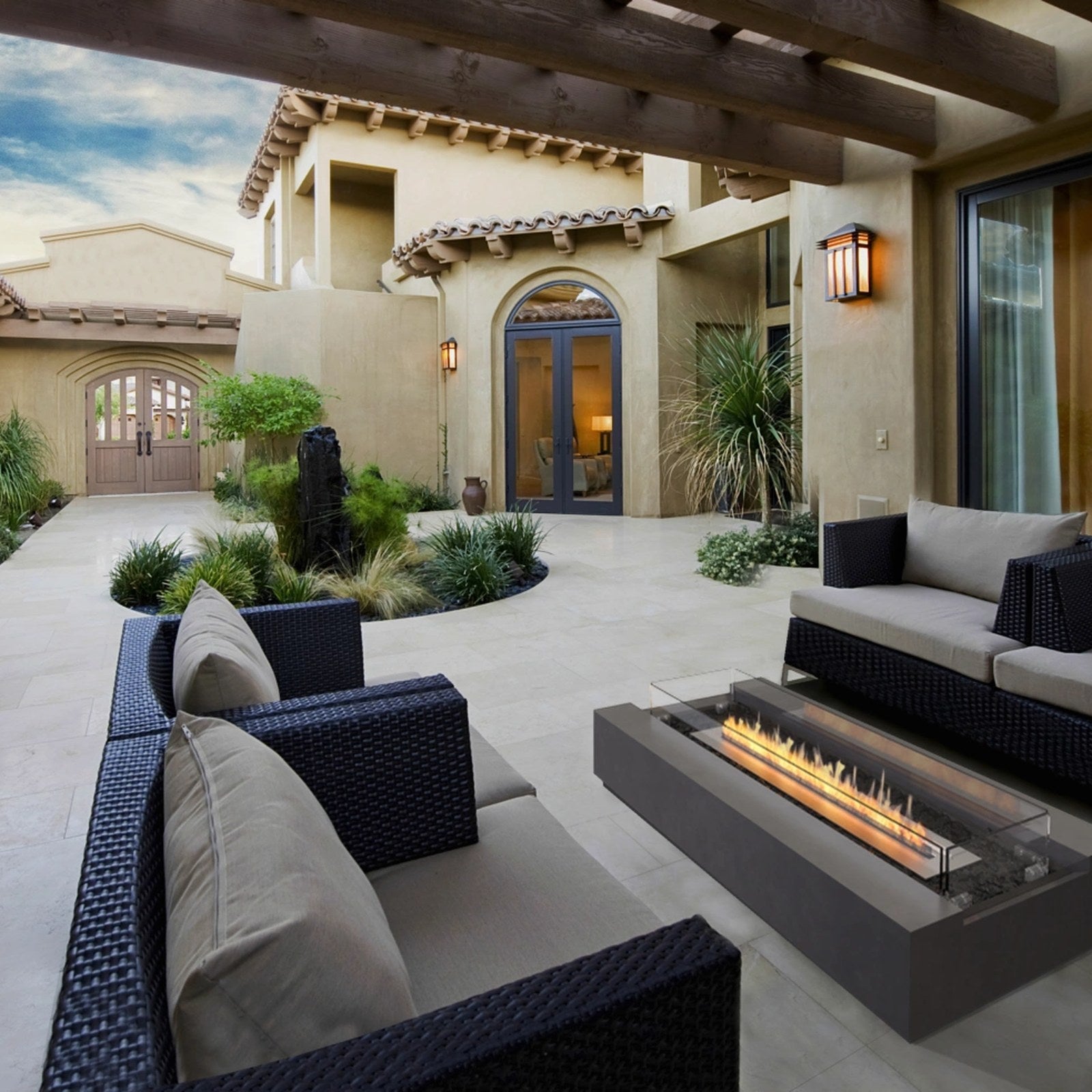 EcoSmart Cosmo 50 fire table lit in a Mediterranean courtyard with outdoor lounge seating.