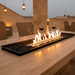 EcoSmart Linear 65 Fire Pit Kit with Stainless Steel burner featuring a modular design, placed on a table in an elegant outdoor setting with the flames burning