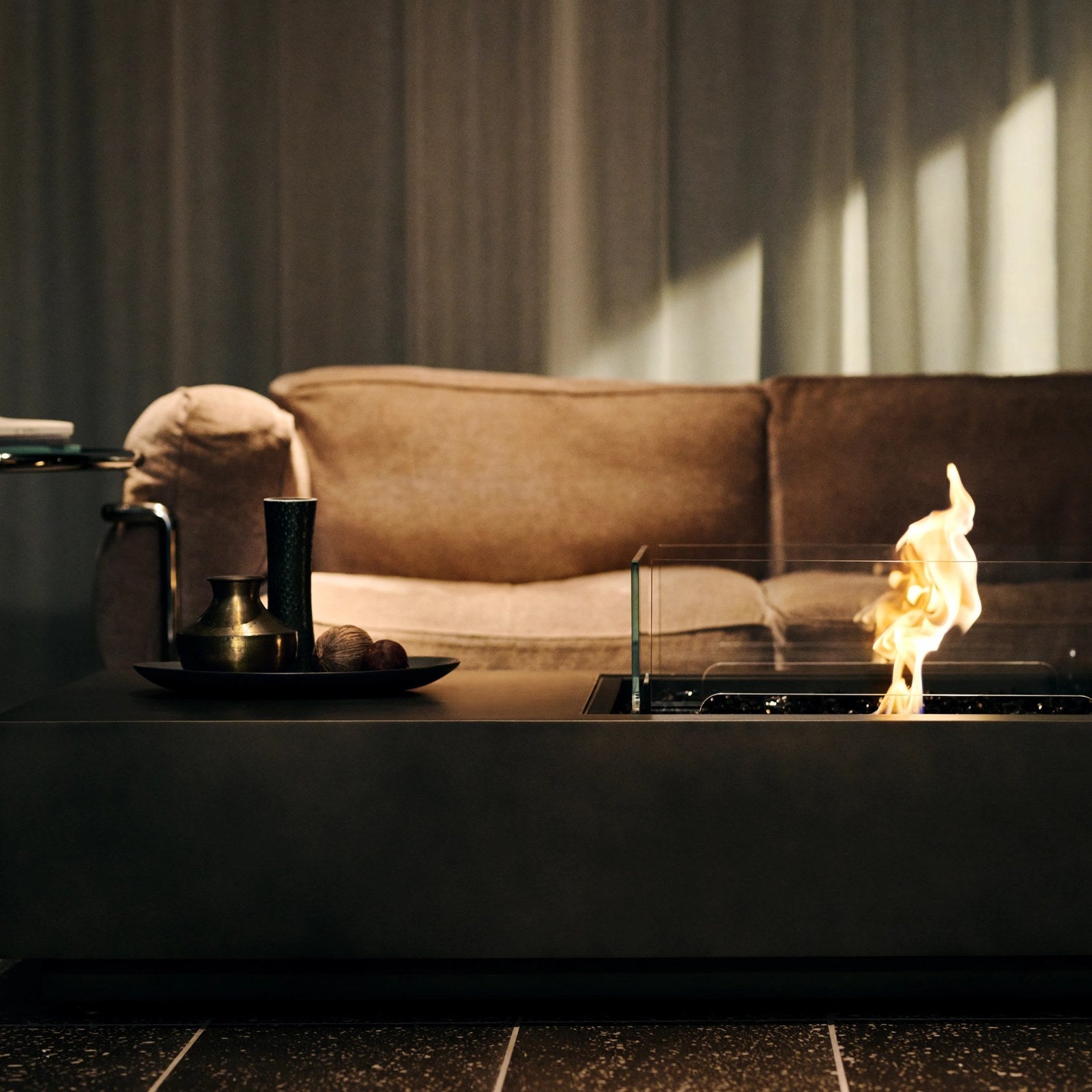 EcoSmart Manhattan 50 fire table in Graphite fluid concrete with the bioethanol flame lit in a warm evening living room.