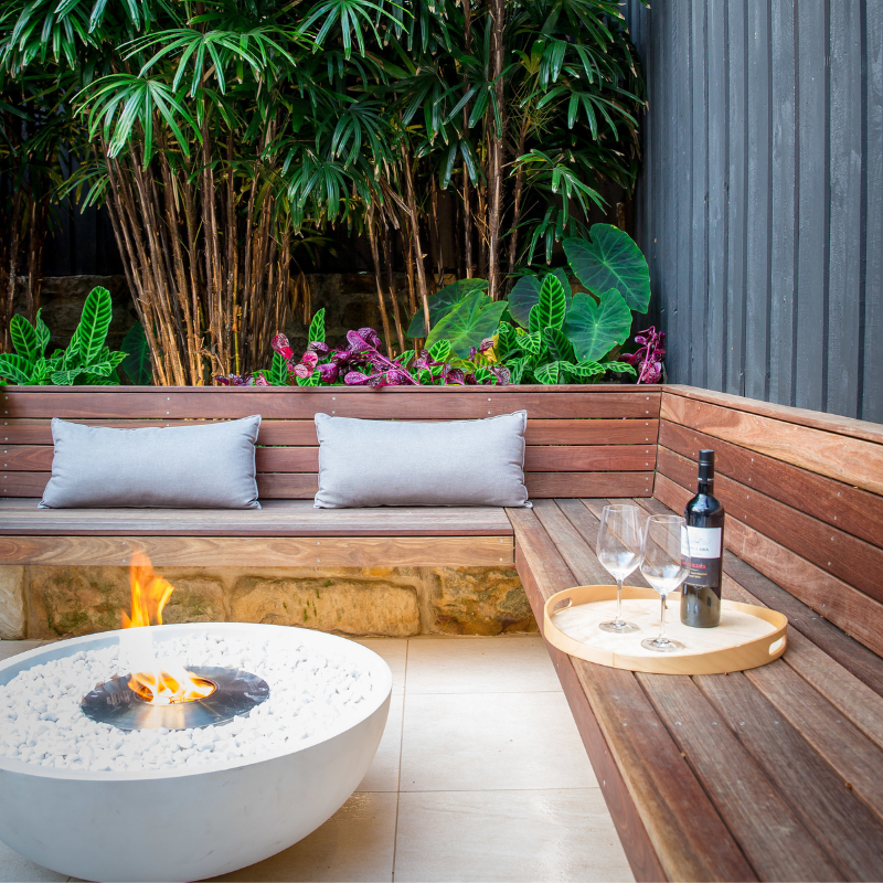 EcoSmart Mix 850 Fire Pit in Bone finish on an outdoor patio with bench seating and wine glasses.