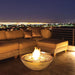 EcoSmart Mix 850 fire pit bowl lit on a rooftop terrace with a city skyline at night.