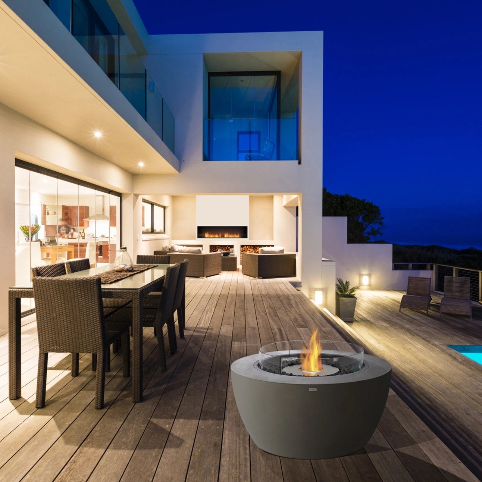 EcoSmart Pod 40 fire pit bowl on an alfresco poolside deck with dining at dusk.