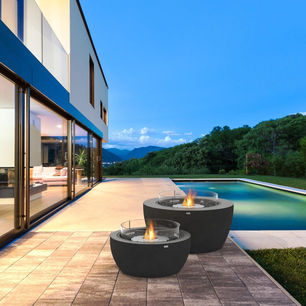 EcoSmart Pod 40 fire pit bowls lit on a poolside deck at dusk beside a modern home.