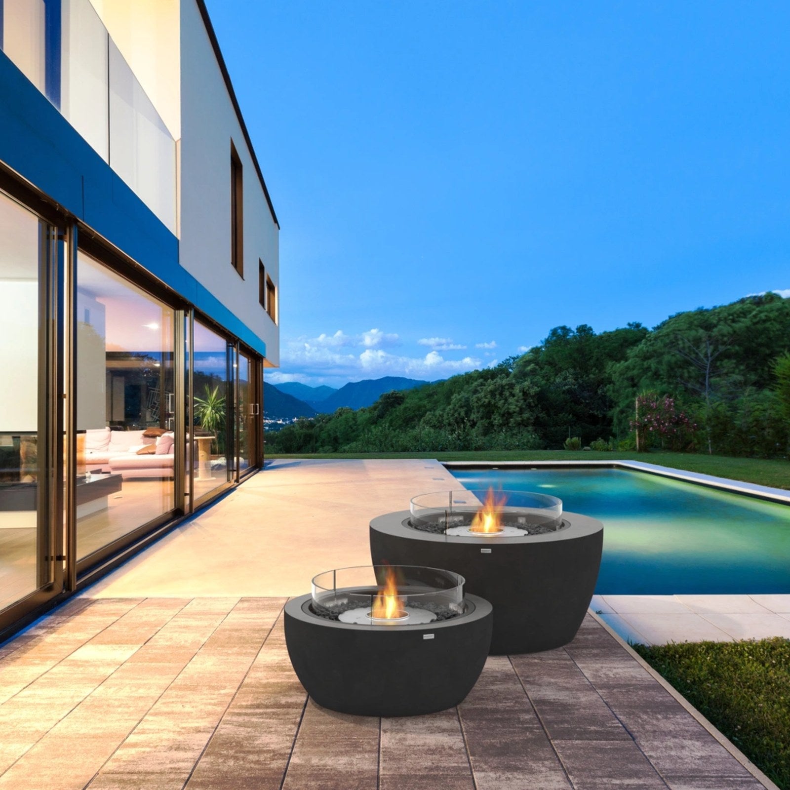 EcoSmart Pod 40 fire pit bowls lit on a poolside deck at dusk beside a modern home.
