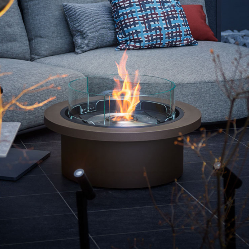 EcoSmart Round 20 Fire Pit Kit placed in an outdoor setting, surrounded by contemporary seating and glass elements, creating an elegant atmosphere.
