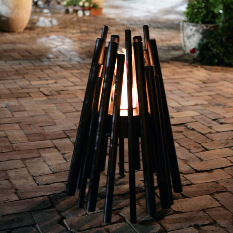 EcoSmart Stix Fire Pit black finish creating ambience on outdoor brick patio at night