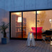 EcoSmart Stix fire pit lit in a concrete courtyard at dusk beside a designer armchair.