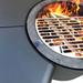 Close-up of the Fabrizio Fire Pit in use with flames and stacked firewood beneath the grill plate, showing the fire pit’s cooking grate and active outdoor heating function.