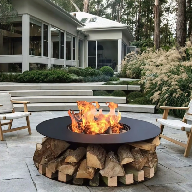 Modern courtyard scene featuring the Fabrizio Fire Pit burning with visible flames, surrounded by lounge chairs in a landscaped residential outdoor setting.