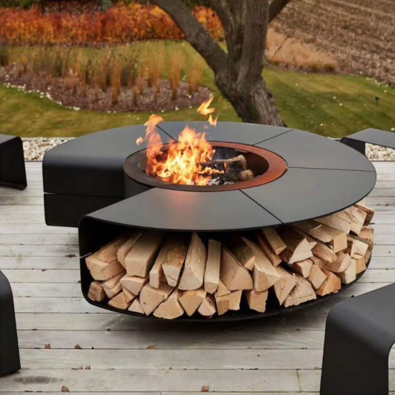 Fabrizio Fire Pit placed on a timber deck with fire burning in the centre and stacked log storage underneath, shown as a modern outdoor heating feature for entertaining spaces.