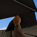 Hand adjusting the rain gutter fabric channel between two umbrella panels
