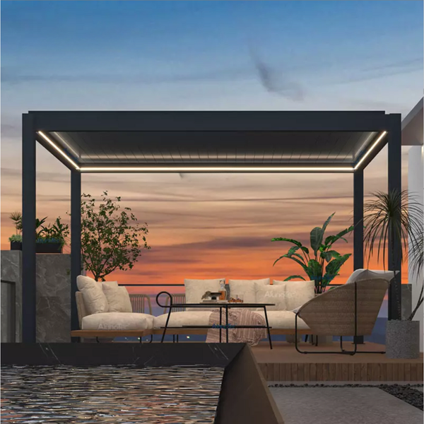 Kustom V Pro in charcoal on a terrace at sunset, louvres closed with a perimeter light line, lounge and dining beneath, water beyond