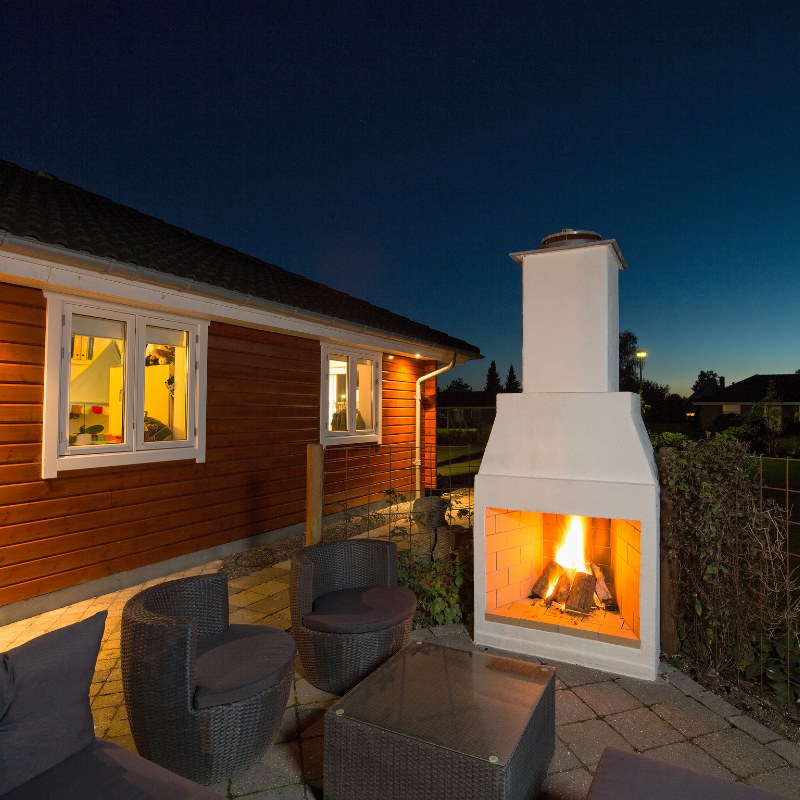 Front product shot of the Ochre Living Hotham Complete Fireplace Kit with fire lit inside the firebox and no lower log storage shown, isolated on a plain background for outdoor fireplace kits Australia.