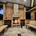 Ochre Living Hotham Complete Fireplace Kit at night beside a timber-clad house with outdoor lounge seating and a bright fire burning, showing an outdoor fireplace with chimney Australia in an evening setting.