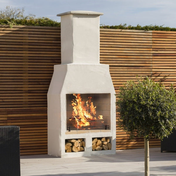 Ochre Living Hotham Complete Fireplace Kit with under log store, fire lit against a timber slat fence